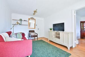 - un salon avec un canapé rose et une télévision dans l'établissement Homely 5 Bed House - 15 Mins to Cardiff City, à Cardiff