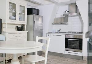 a white kitchen with a white table and a stove at CasaMarchi in Sottomarina