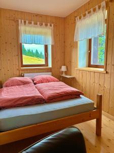 a bedroom with a bed with red sheets and two windows at DOMŽALSKI DOM na Veliki Planini in Stahovica
