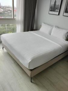 a large white bed in a room with a window at Veranda Residence Pattaya By Suia in Na Jomtien