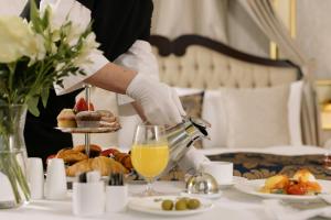 a woman is preparing a table with a tray of food at HOTEL SJ PRIDE in Bhubaneshwar
