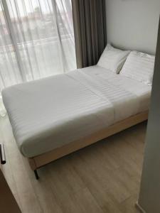 a large bed in a room with a window at Veranda Residence Pattaya By Suia in Na Jomtien