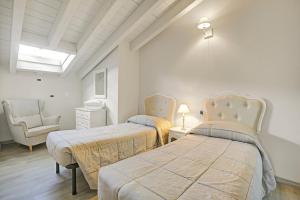 ein Schlafzimmer mit 2 Betten und einem Stuhl in einem Zimmer in der Unterkunft Agriturismo Cascina Crocelle - Lake View and Heated Pool in Padenghe sul Garda