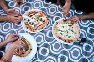 a group of people eating pizzas on a table at Camping Can Coromines in Maia de Montcal