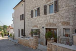 a stone building with windows and plants on a street at Holiday apartments by the sea in Funtana