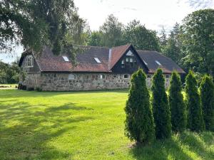 a large stone house with trees in front of it at Denderi in Vaidava