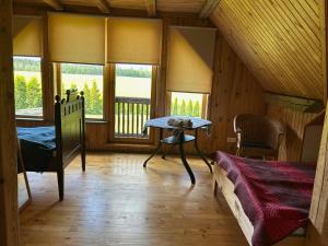 a room with a bed and a table and windows at Denderi in Vaidava