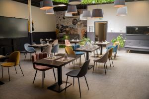 a restaurant with tables and chairs and a large screen at Hôtel d'Angleterre, Salon-de-Provence in Salon-de-Provence