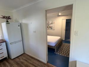 a small bedroom with a bed and a refrigerator at Bruns Beach Garden Apartment - Central, Comfortable & Close to the beach in Brunswick Heads +2 photos
