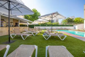 a group of lounge chairs and umbrellas next to a swimming pool at Hotel Bell Aire in L'Estartit