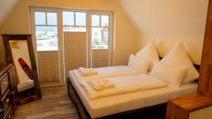 ノイハルリンガージールにあるFischerhäuschen am Kurpark-See ohne Schwimmbad- und Saunanutzungの白いシーツと窓のあるベッドのある寝室