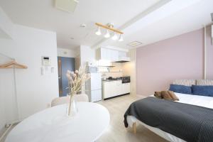 a bedroom with a bed and a table and a kitchen at シティラデファンス - 2025年6月室内リニューアル in Sapporo