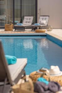 a swimming pool with two lounge chairs next to a swimming pool at Villa Amorosa, Luxury Villa with Large heated Pool & Sea View, Lošinj Island in Nerezine