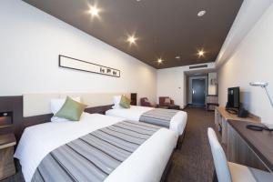 a hotel room with two beds and a television at HOTEL MYSTAYS PREMIER Kanazawa in Kanazawa