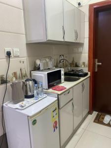 a small kitchen with a microwave and a refrigerator at نزل اكنان للشقق المخدومة in Najran