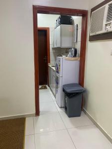 a small kitchen with a refrigerator and a trash can at نزل اكنان للشقق المخدومة in Najran +3 photos