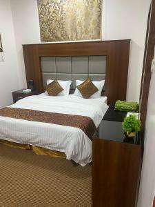 a bedroom with a large bed with a wooden headboard at نزل اكنان للشقق المخدومة in Najran