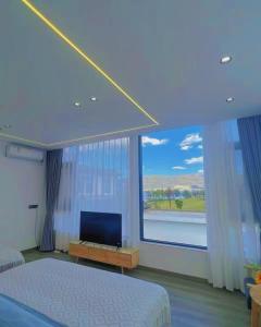 大理Yunqi Canghai Yunyin Secret Realm Jianbai Art Designer Travel and Vacation Beautiful Homestay Erhai Store的一间带电视和大窗户的卧室