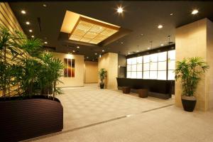 a lobby with potted plants in a building at HOTEL MYSTAYS PREMIER Kanazawa in Kanazawa