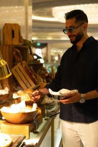 a man holding a plate of food in a store at The Ritz-Carlton, Riyadh in Riyadh +100 photos