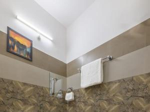a bathroom with a painting and towels on a wall at Snowfall View Home Kasauli Operated By Splendid Hotels in Kasauli