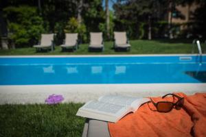 a book and glasses sitting on a blanket next to a swimming pool at Corvetto Residence Porto Di Mare in Milan