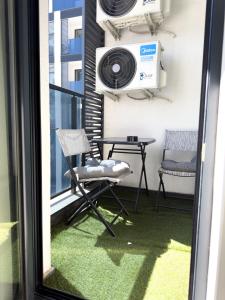 プロブディフにあるModern 1BR Apartment with Free Street Parking and free Gym Passのバルコニー(テーブル、椅子2脚、ファン付)