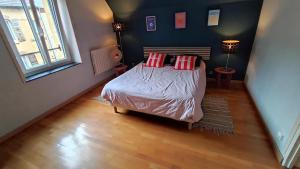 a bedroom with a bed with red pillows on it at La maison du voyageur toque in Charleville-Mézières