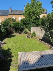a garden with a wooden walkway in front of a house at La maison du voyageur toque in Charleville-Mézières
