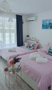 two beds in a room with pink sheets and a table at Saturn ROOMS in Saturn