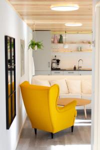 a yellow chair in a living room with a couch at Colorful brand new apartment with free parking in Tórshavn