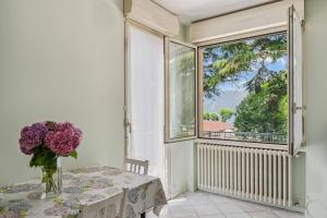 a vase of flowers on a table in a room with a window at Green Village Accommodations in Colico