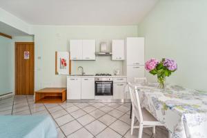a kitchen with a table with a vase of flowers on it at Green Village Accommodations in Colico