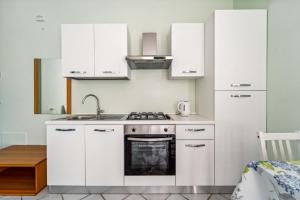 a kitchen with white cabinets and a stove top oven at Green Village Accommodations in Colico