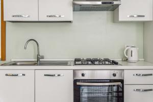 a kitchen with white cabinets and a stove and sink at Green Village Accommodations in Colico