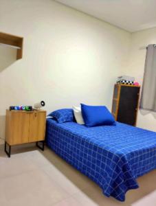 Un dormitorio con una cama azul y una mesa. en Apartamento no centro de Tatuí 2, en Tatuí