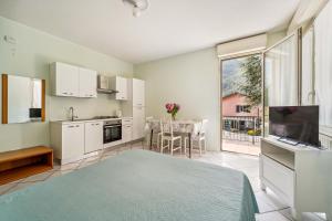a kitchen with white cabinets and a table with a television at Green Village Accommodations in Colico