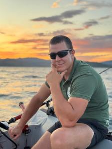 a man sitting on a boat in the water at Kamp Bilećko Jezero in Trebinje