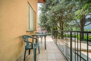 a balcony with a table and chairs and trees at Green Village Accommodations in Colico