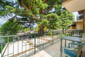a balcony with a table and chairs and a tree at Green Village Accommodations in Colico