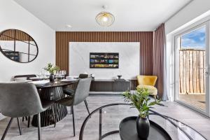 Una sala de estar con mesa de comedor y sillas. en Spacious 4BR Home, Garden & Parking, Sleeps 8, en Brimsdown Station