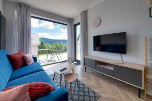 a living room with a blue couch and a large window at RentPlanet - Apartamenty Schroniskowa in Szklarska Poręba