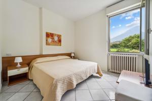 a bedroom with a bed and a large window at Green Village Accommodations in Colico