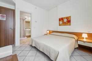 a bedroom with a bed and a desk and a bathroom at Green Village Accommodations in Colico