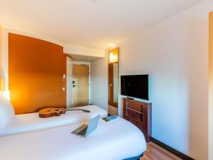 a hotel room with two beds and a flat screen tv at Hotel Ibis Lisboa Sintra in Sintra