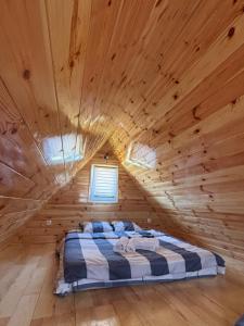 een bed in een blokhut met een houten plafond bij Cottage Martina in Žabljak