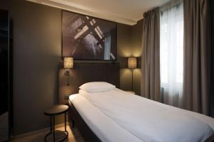 a bedroom with a large white bed and a window at Scandic Vulkan in Oslo