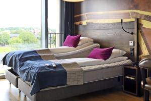 a bedroom with two beds with purple pillows at Scandic Vulkan in Oslo