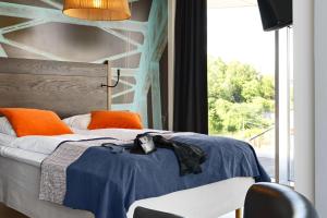 a bedroom with a bed with orange pillows and a window at Scandic Vulkan in Oslo
