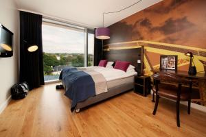 a bedroom with a bed and a desk and a window at Scandic Vulkan in Oslo